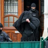 Polizeibeamte führen einen Tatverdächtigen aus einem durchsuchten Haus.