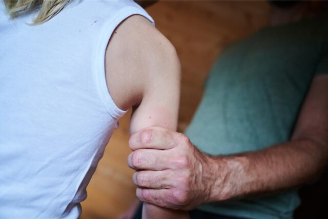 Ein Mann hält ein Kind fest am Arm