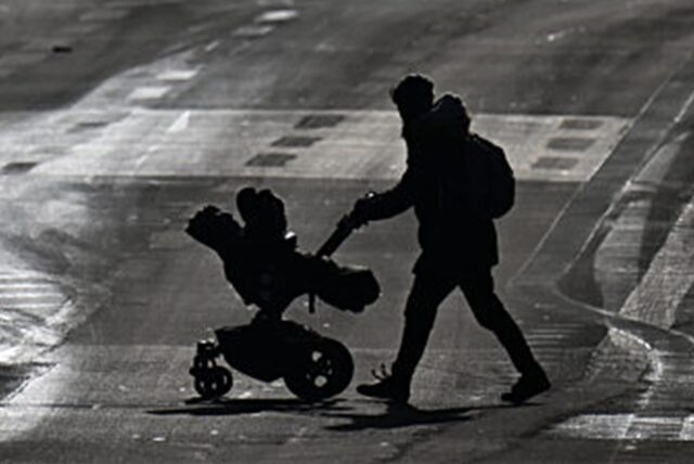 Eine Frau mit einem Kinderwagen geht über eine Straße. (Symbolbild).