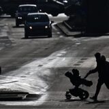 Eine Frau mit einem Kinderwagen geht über eine Straße. (Symbolbild).