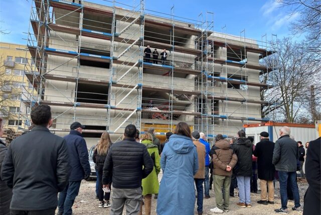 Menschenmenge steht vor Rohbau