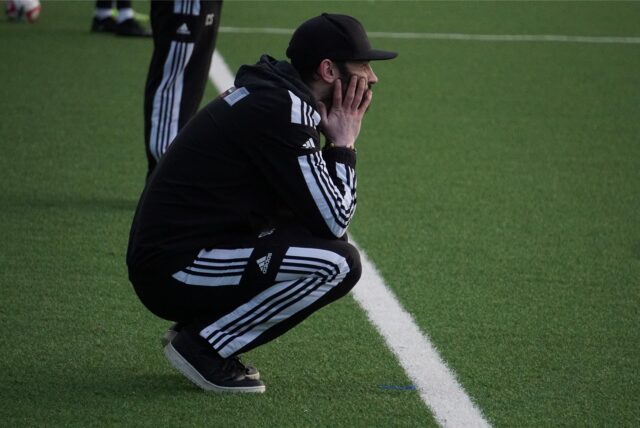 David Sawatzki, Trainer des BV Brambauer, kniet am Spielfeldrand.