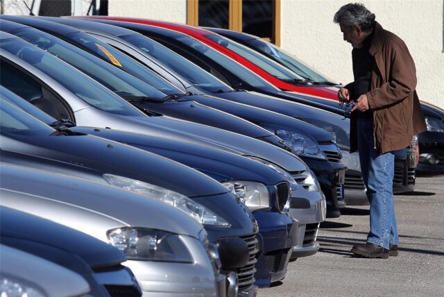 Ein Mann steht vor einer Reihe Autos.