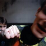Symbolbild, erhobene Hand. Zwei Personen sind unscharf zu sehen.