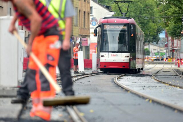 Arbeiter bei Gleisbauarbeiten auf der Linie U43 mit einer Bahn im Hintergrund.