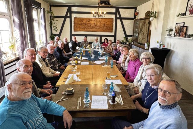 Alte Menschen sitzen um einen großen Tisch herum.