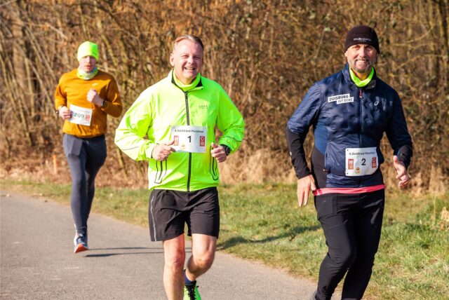 Drei Menschen joggen über eine Straße