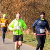 Drei Menschen joggen über eine Straße
