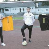 Sedat Sener steht mittig, neben ihm halten zwei Männer Trikots.