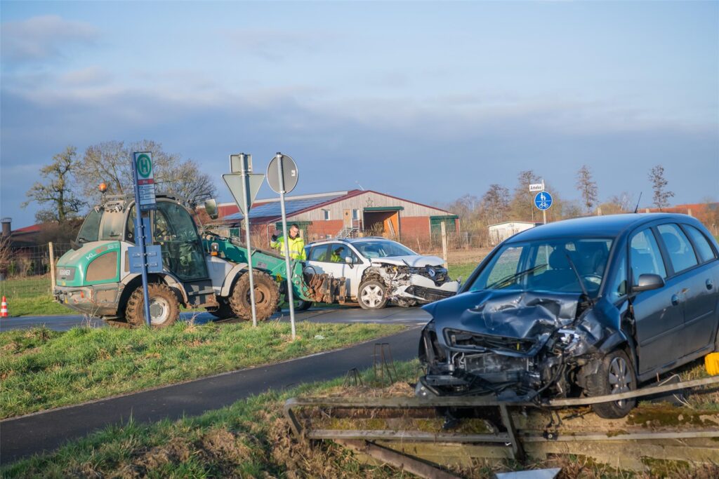 Zwei durch einen Unfall beschädigte Auto und ein Traktor auf der Straße, die Abschleppung wird vorbereitet. Zwei durch einen Unfall beschädigte Auto und ein Traktor auf der Straße, die Abschleppung wird vorbereitet.