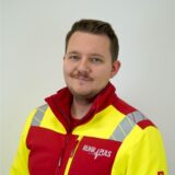 Links Notfallsanitäter Lukas Tschufenig in Arbeitsmontur, rechts der Tacho eines Autos