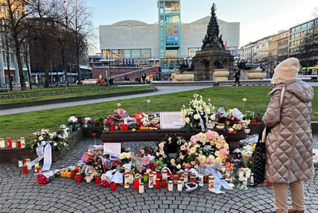Eine Frau steht an einem Ort des Gedenkens für die Opfer einer Todesfahrt mit zwei Toten und mehreren Verletzten am Paradeplatz in der Innenstadt vor Blumen und Kerzen.
