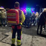 Der Notfallsanitäter Lukas Tschufenig steht mit Rettungsausrüstung vor einer beleuchteten Bühne.