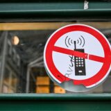 Ein Schild mit einem durchgestrichenen Handy-Symbol weist in einer Schule auf ein Handyverbot hin.