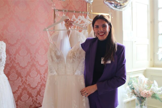Katharina Pins bei der Hochzeitsmesse im Schloss Herten am 23.02.2025, sie zeigt ein Kleid mit Spitze und Blättermuster.