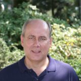 Meinolf Schmidt steht vor einer Grünanlage auf seinem Kandidatenfoto für die Kommunalwahl 2020.