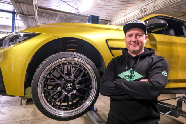 Ein Mann steht mit verschränkten Armen vor einem Sportwagen, der auf einer Hebebühne in einer Werkstatt in Recklinghausen steht.
