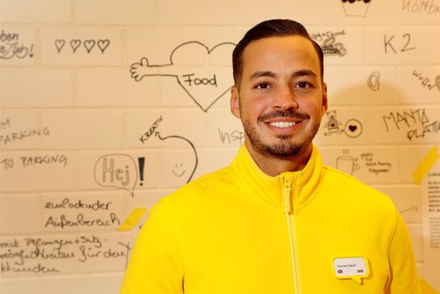Younes Sakali, Leiter von Ikea in Kamen, vor einer Wand mit Wörtern und Zeichnungen.
