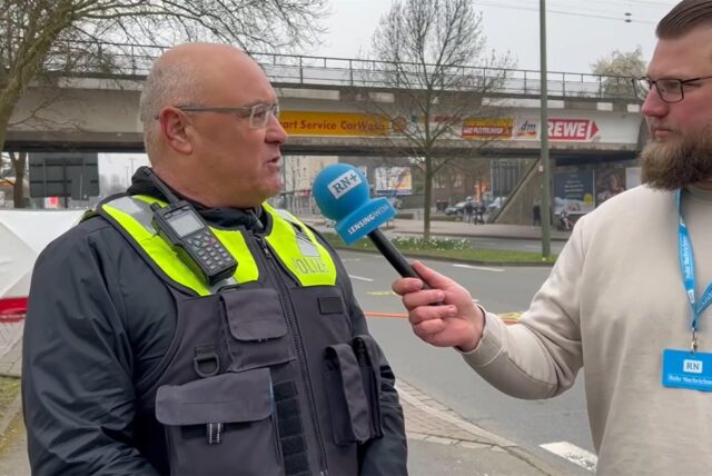Ein Reporter spricht mit einem Polizeisprecher.