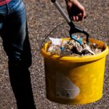 Person mit gelbem Mülleimer