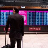 Ein Mann steht bei Warnstreiks von Verdi am Hauptstadtflughafen Berlin-Brandenburg BER vor der Anzeige mit gestrichenen Flügen.