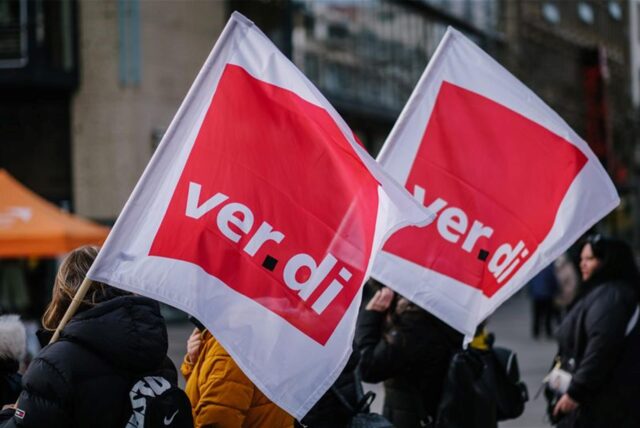Beschäftigte demonstrieren mit Verdi-Fahnen.