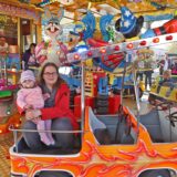 Eine Mutter sitzt mit ihrem Kind auf einem Kinderkarussell auf der Märzkirmes 2025 in Heeren-Werve.