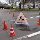 Trennlinien zwischen den Abstellflächen werden auf einem Parkplatz mit weißen Farbmarkierungen erneuert.