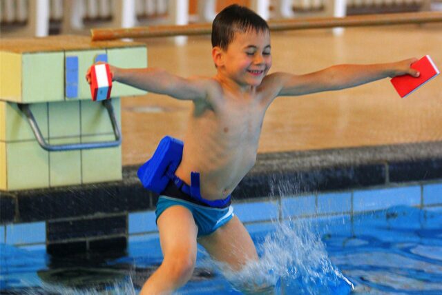 Ein Junge springt ins Schwimmbecken.
