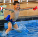 Ein Junge springt ins Schwimmbecken.