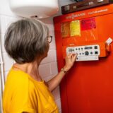 Eine Frau justiert die Steuerung eines Viessmann VitoCell-uniferral Heizkessels. Der Kessel trägt ein Energieeffizienzlabel der Klasse D.