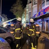 Zwei Feuerwehrmänner stehen während des Brandeinsatzes an der Rheinischen Straße in Dorztmund auf dem Bürgersteig.