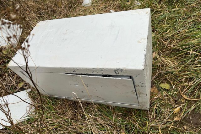 Auf einer Wiese liegt ein hellgrauer Tresor.