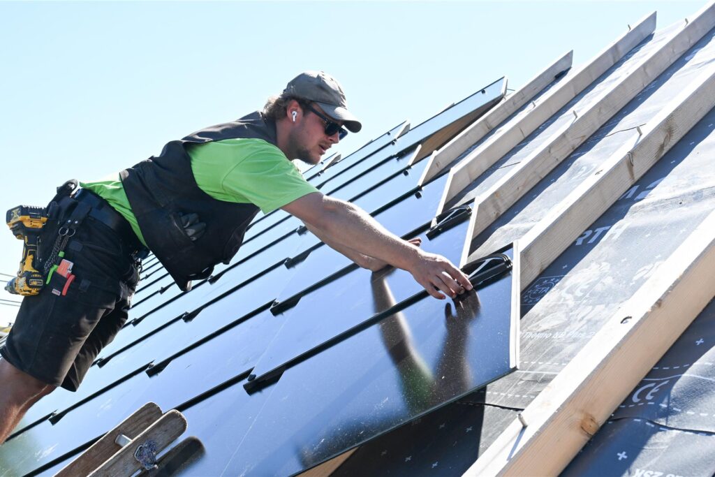 Ein Handwerker installiert eine Photovoltaik-Anlage auf einem Dach. Ein Handwerker installiert eine Photovoltaik-Anlage auf einem Dach.