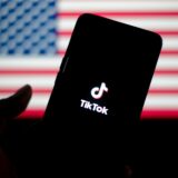 Das TikTok-Logo wird auf einem Smartphone mit der Flagge der Vereinigten Staaten im Hintergrund angezeigt.