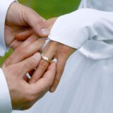 Der Bräutigam steckt seiner Braut den Ehering an den Ringfinger.