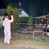 Mann im Schutzanzug macht Fotos an einer ausgebrannten Hütte.