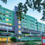 Links eine Frau in einem Krankenhaus, die sich coronakonform einkleidet, rechts die Knappschaft Kliniken Kamen.