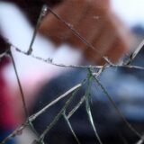 Eine geballte Faust ist hinter einer zersplitterten Glasscheibe zu sehen.