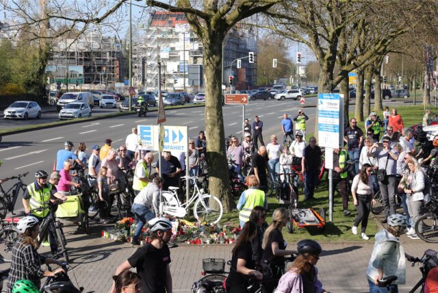 Menschen stehen an der Unfallstelle um eine Ghostbike herum.