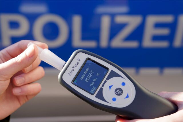 Ein Polizist hält ein Alkohol-Messgerät in der Hand.