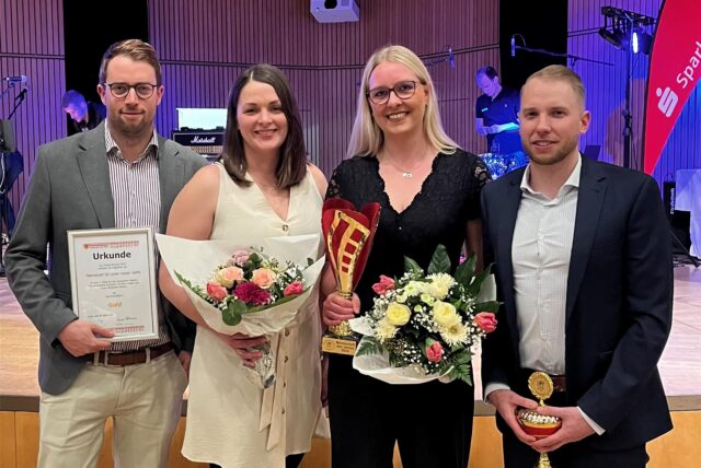 Matthias Hövener (v.l.n.r.), Lara Hövener, Katharina Stember und Steffen Renze stehen mit ihren Urkunden und Blumen vor der Bühne des Hansesaals.
