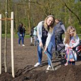Eine Frau und ein Mädchen arbeiten in Unna bei einem Pflanzfest im Kurpark mit Schaufeln neben einem frisch gesetzten Baum.
