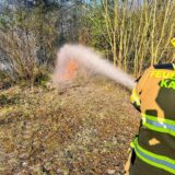Ein Feuerwehrmann löscht mit Wasser aus einem Schlauch Flammen.