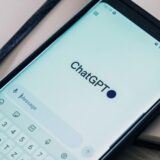 Links ein Smartphone, das die App ChatGPT anzeigt, rechts der Blick von der Adener Höhe in Bergkamen.