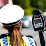 Eine Polizistin misst mit einem Laser die Geschwindigkeit eines Autos.