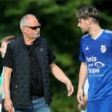 Peter Seifert läuft cool über einen Sportplatz und unterhält sich mit Kerem Senderovic.