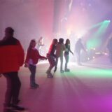 Menschen sind in der Eishalle in Bergkamen bei Disco-Beleuchtung mit Schlittschuhen auf dem Eis unterwegs.