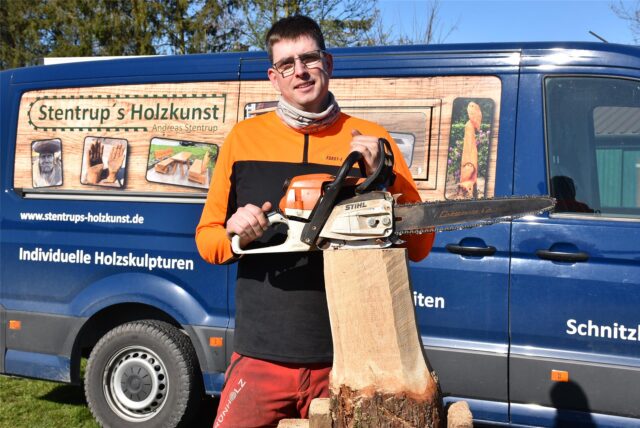 Andreas Stentrup mit einem Baumstamm, auf dem er seine Motorsäge ablegt.