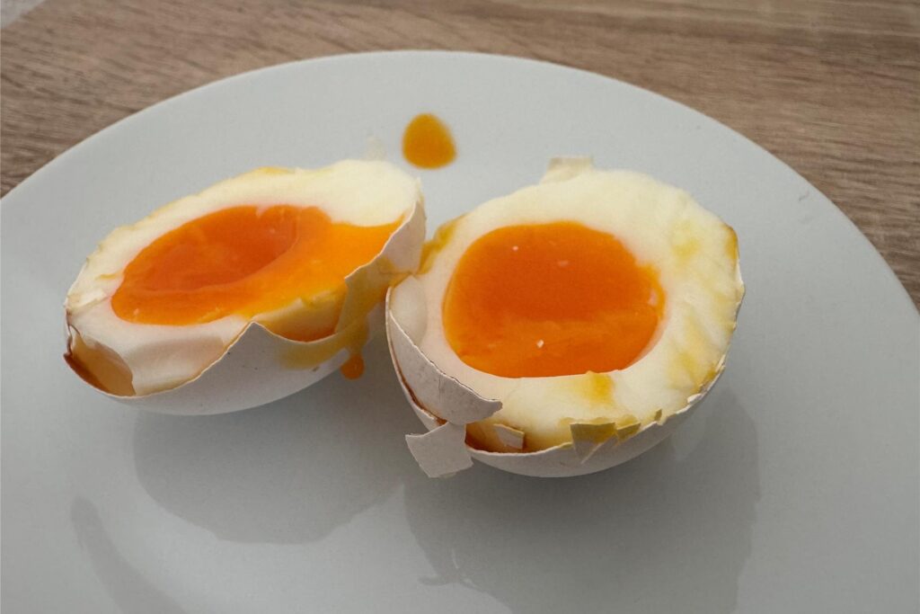 Ein in zwei Hälften geteiltes, wachsweich gekochtes Ei, das im Airfryer gegart wurde.